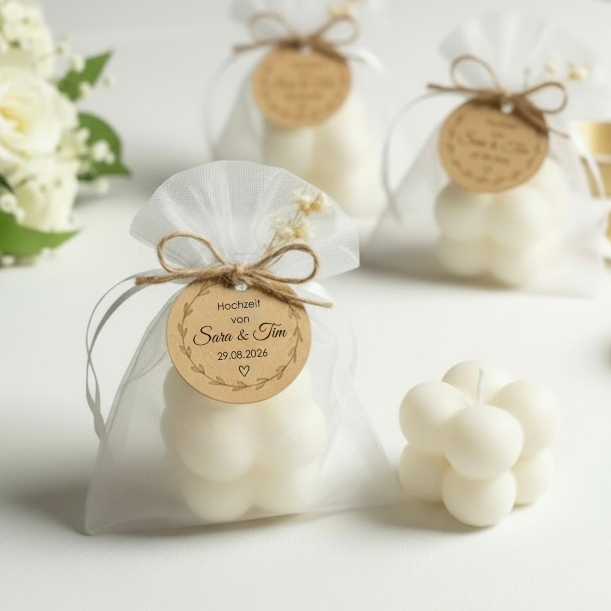 Personalisierte Bubble Kerze aus cremeweißem Sojawachs als Gastgeschenk zur Hochzeit, im weißen Organza-Säckchen mit Trockenblumen und personalisiertem Anhänger.