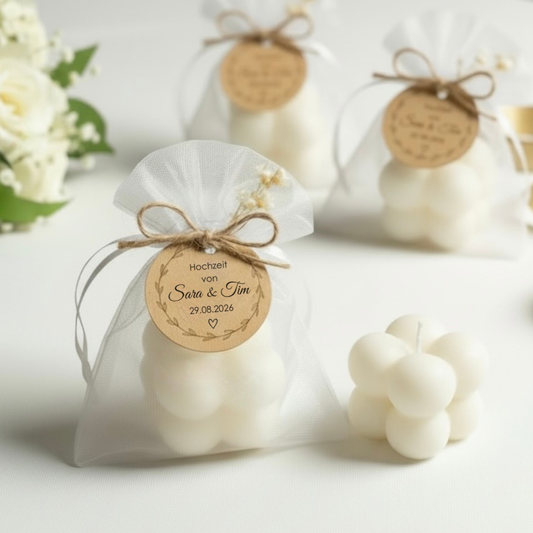 Personalisierte Bubble Kerze aus cremeweißem Sojawachs als Gastgeschenk zur Hochzeit, im weißen Organza-Säckchen mit Trockenblumen und personalisiertem Anhänger.